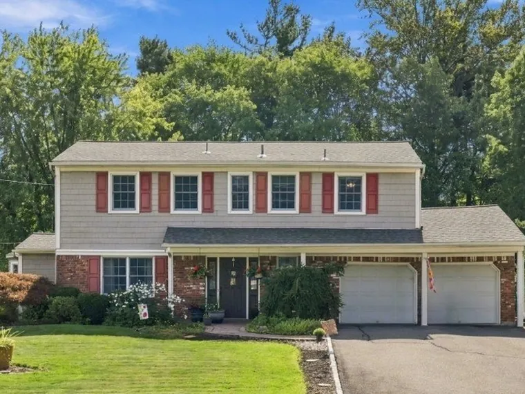 Two-story colonial with gray shingle siding, red shutters, a brick front and a two-car garage at 41 Fleetwood Dr, Rockaway, New Jersey