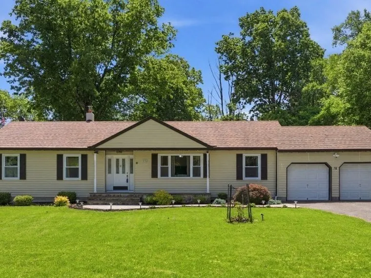 Ranch home with pale yellow siding, dark shutters, a wide lawn and a two-car garage at 76 Marble Hill Rd, Great Meadows, New Jersey